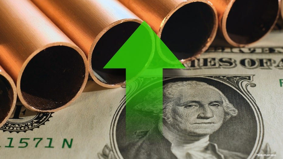 Copper pipes laying on top of dollar bill with a green arrow graphic on top