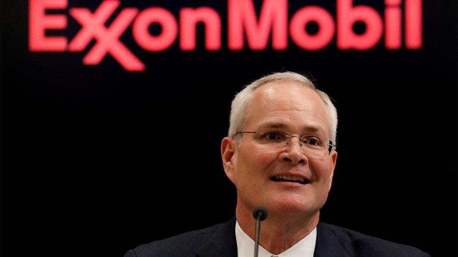 Darren Woods speaking at microphone with ExxonMobil sign in background