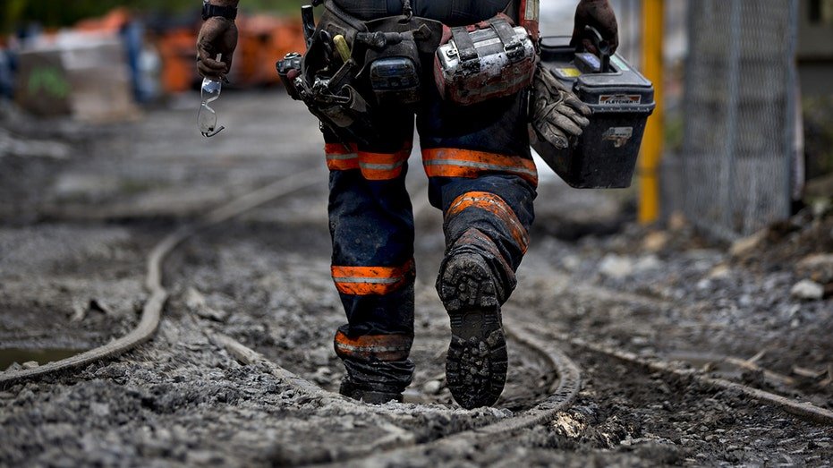 Miner walks next to mantrip shuttle tracks