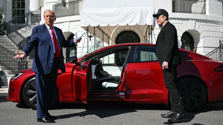 Donald Trump and Elon Musk standing next to a red Tesla outside of the White House