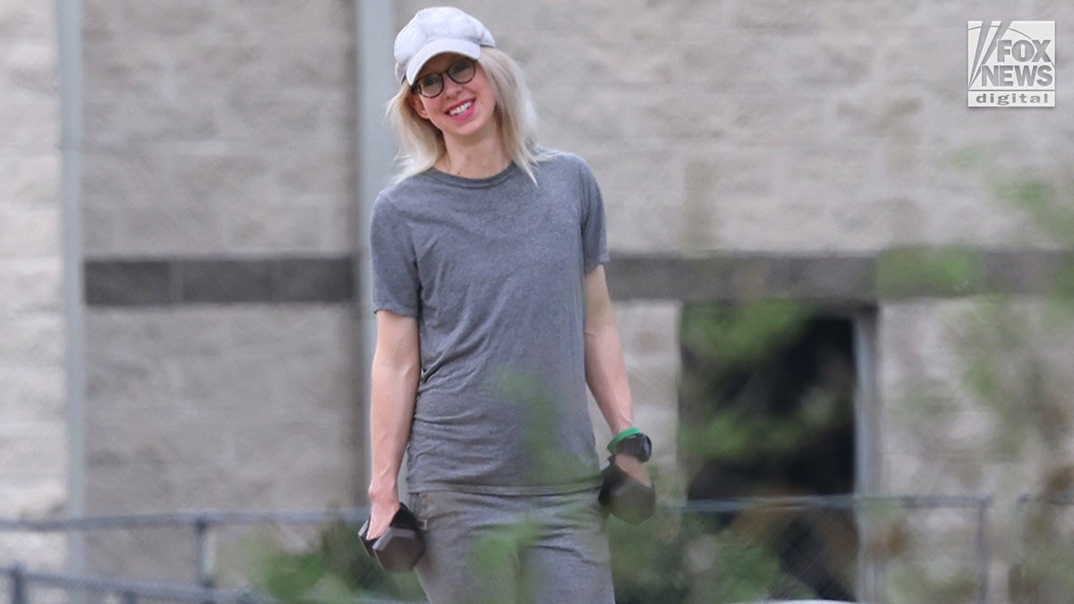 Elizabeth Holmes smiles while holding weights