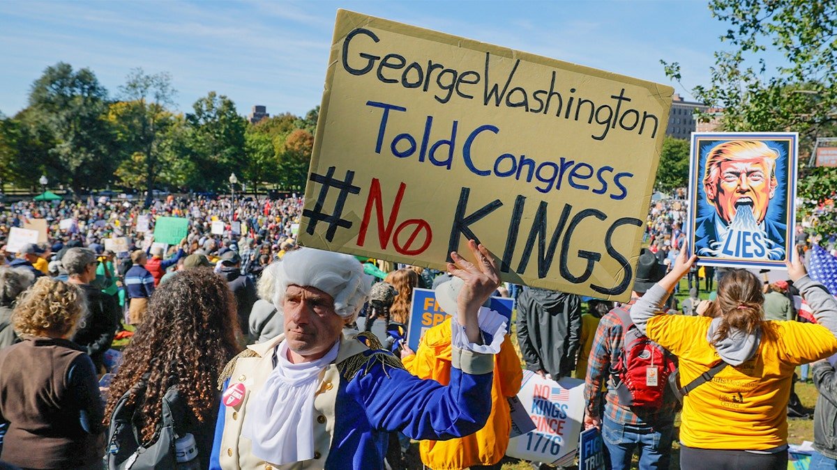 A man dressed as former President George Washington displays a sign during a "No Kings" protest in Boston, Saturday.