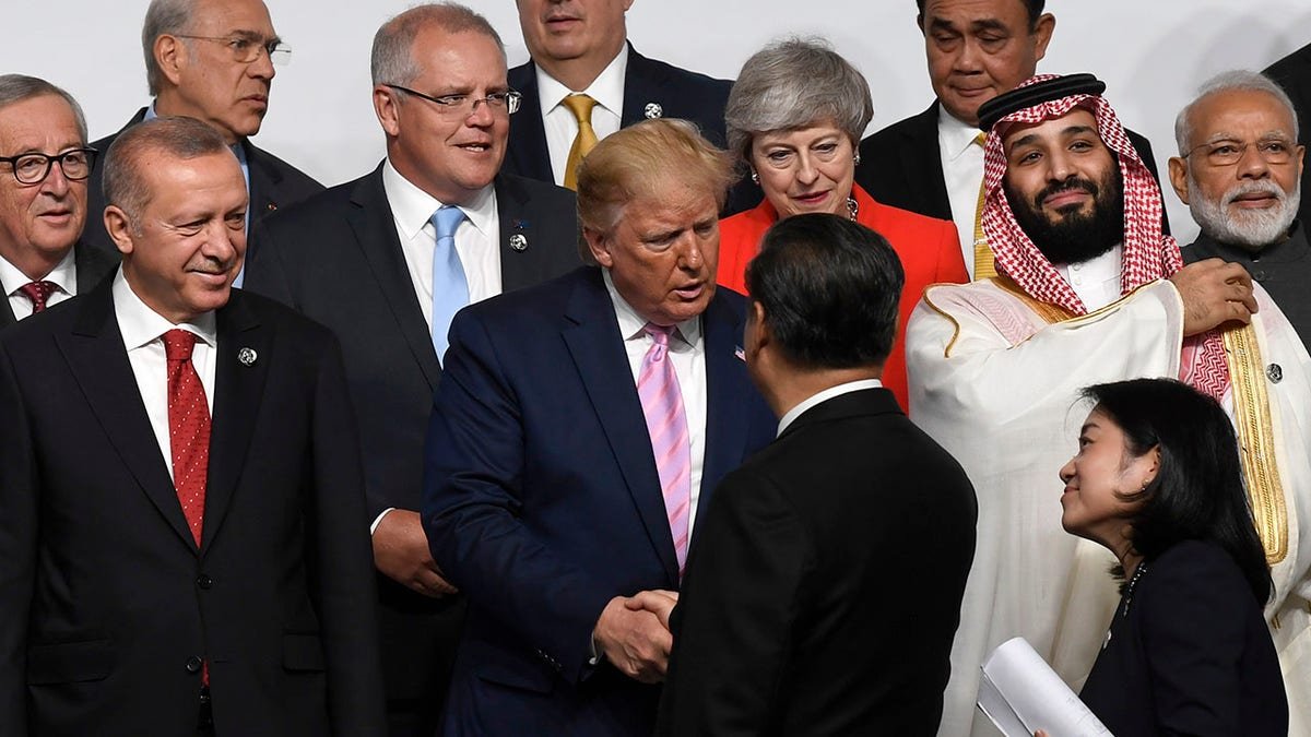 President Donald Trump, center, shakes hands with Chinese President Xi Jinping, as they gather for a group photo at the G-20 summit in Osaka, Japan, June 28, 2019.