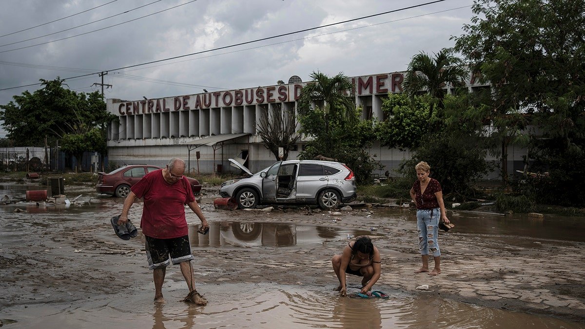 People walking along road covered in murky water