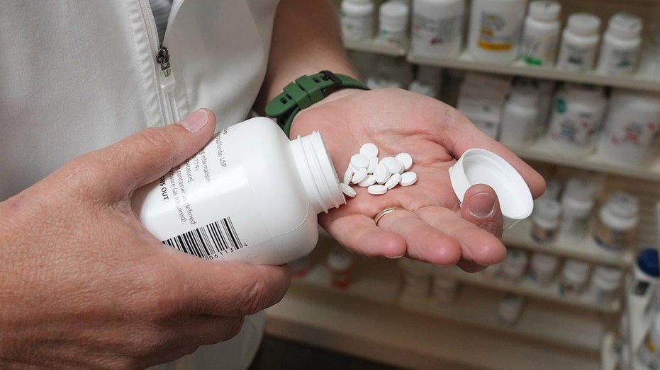 A pharmacist pulls a drug from a shelf inside a pharmacy in Provo, Utah.