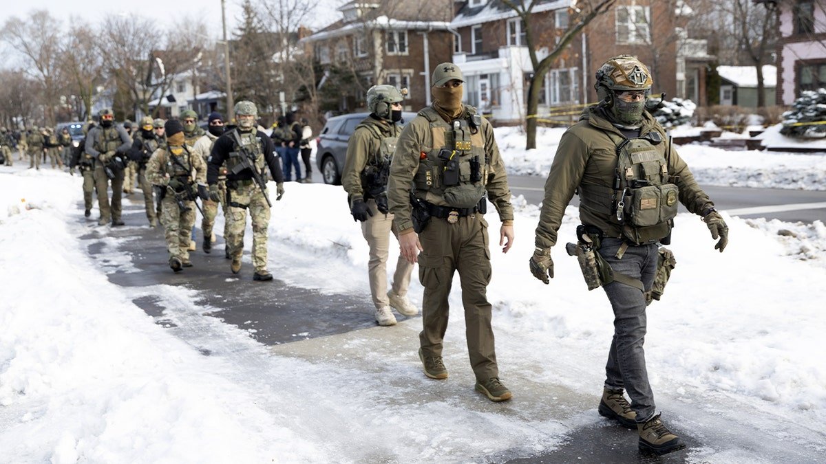 Federal agents walk on a city street in Minneapolis.