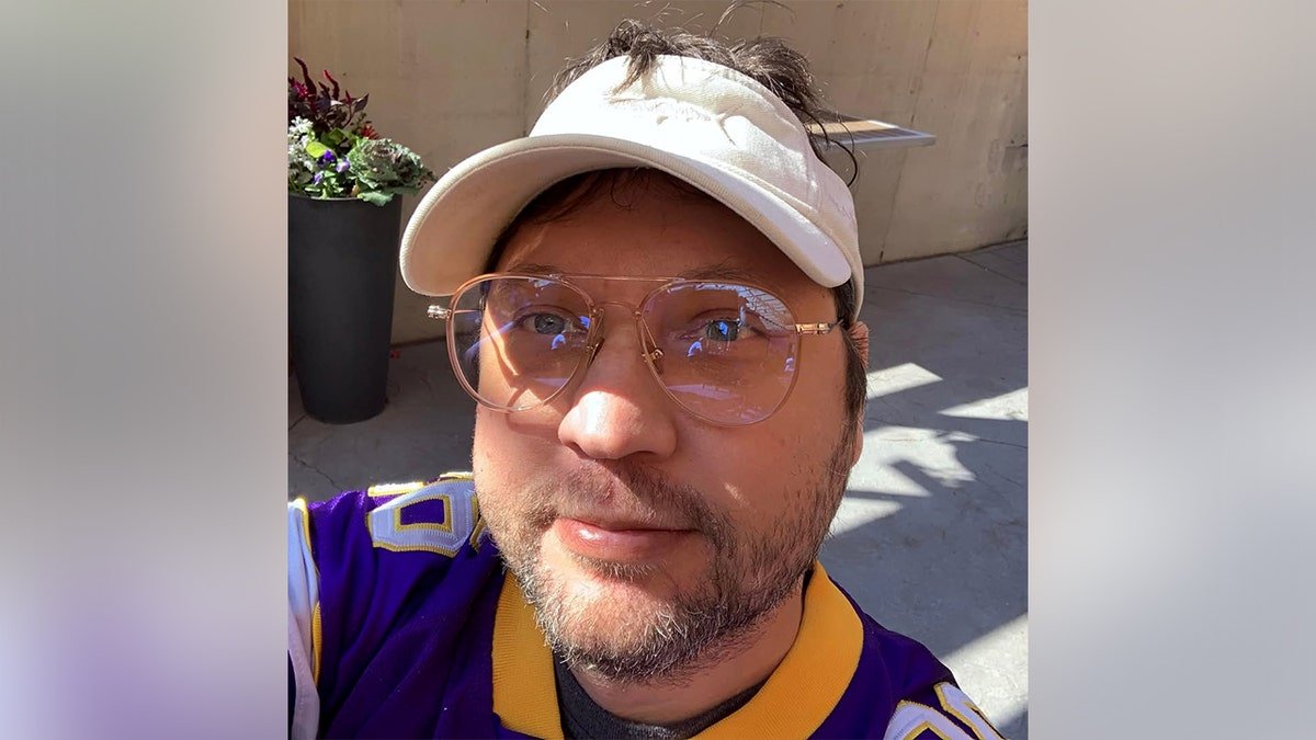 Anthony James Kazmierczak takes a selfie while wearing glasses and a white visor.