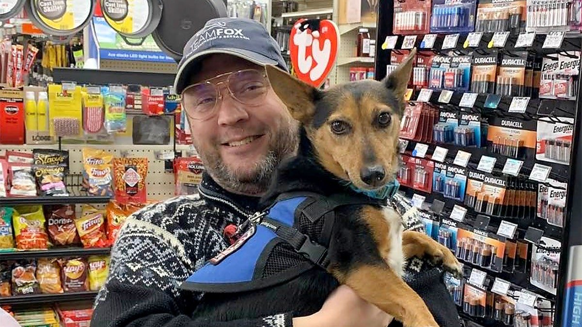 Anthony James Kazmierczak holds a dog and smiles whilst in a store.