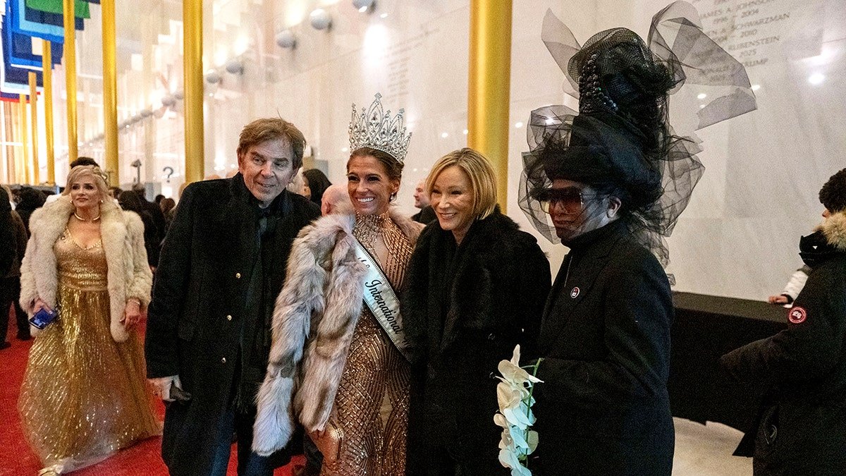 Group of dressed guests posing on red carpet of "Melania" premiere.