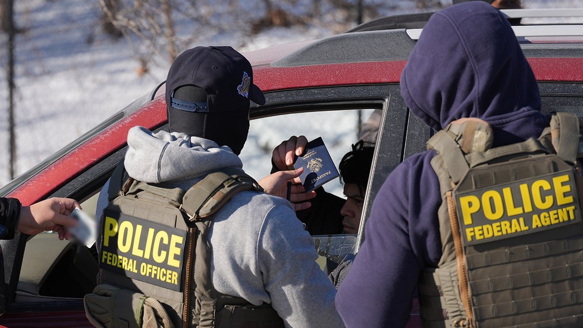 Federal agents conducting a traffic stop as a person holds out a passport and driver's license.