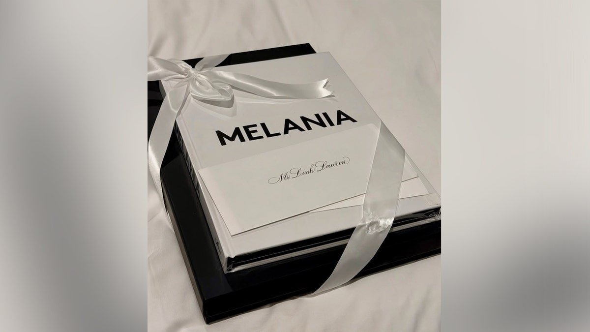 Luxury black presentation box wrapped with a white satin ribbon, featuring a booklet titled 